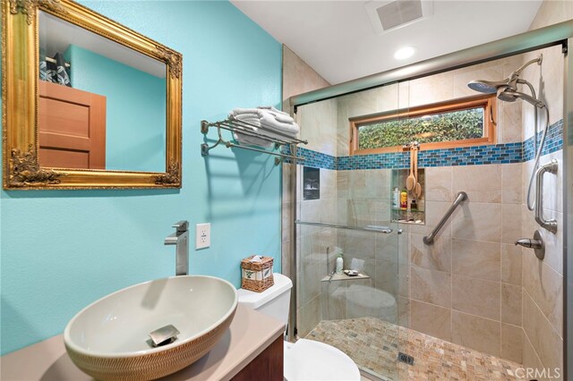 bathroom featuring a shower with door, vanity, and toilet