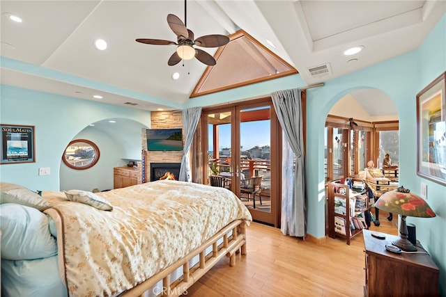 bedroom with high vaulted ceiling, a fireplace, access to outside, ceiling fan, and light wood-type flooring