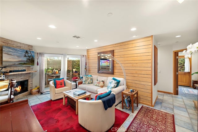 living room featuring light tile patterned floors, wood walls, and a fireplace