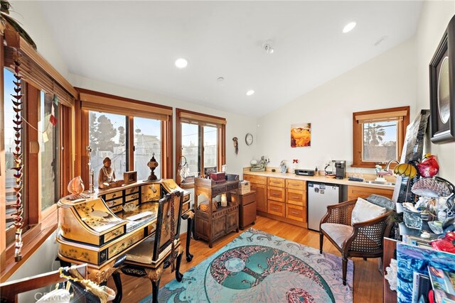 living area featuring lofted ceiling, light hardwood / wood-style flooring, and a wealth of natural light