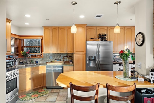 kitchen with pendant lighting, appliances with stainless steel finishes, sink, and decorative backsplash