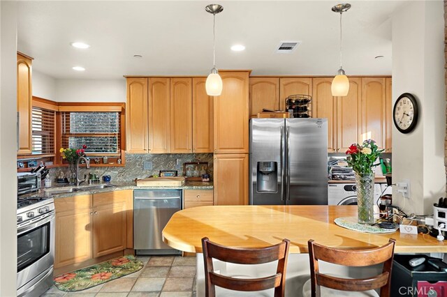 kitchen with decorative backsplash, appliances with stainless steel finishes, sink, and hanging light fixtures