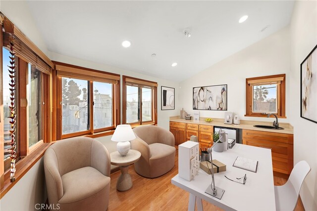 living area with lofted ceiling, sink, and light wood-type flooring