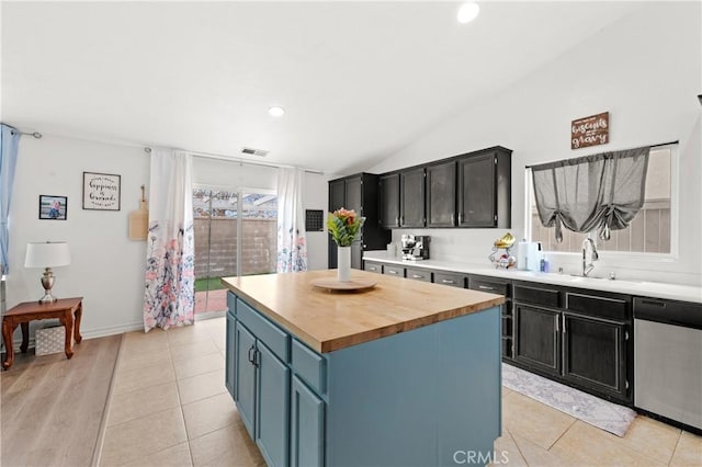 kitchen featuring lofted ceiling, a center island, stainless steel dishwasher, sink, and blue cabinets