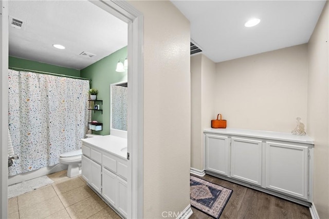 full bathroom with hardwood / wood-style floors, toilet, vanity, and shower / tub combo