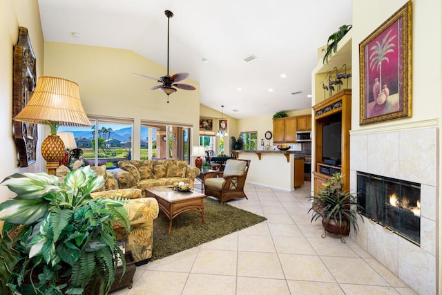 living room featuring lofted ceiling, light tile patterned floors, a tiled fireplace, and ceiling fan