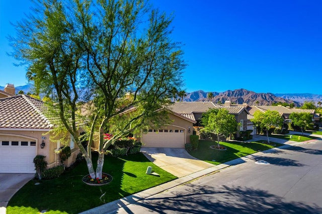 view of front of property with a front lawn, a mountain view, and a garage