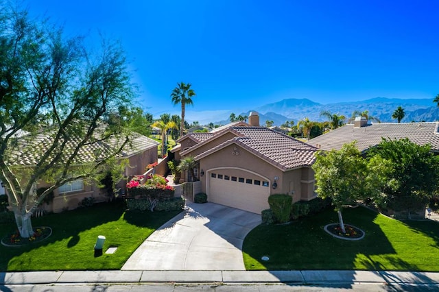 view of front of property featuring a mountain view, a front yard, and a garage