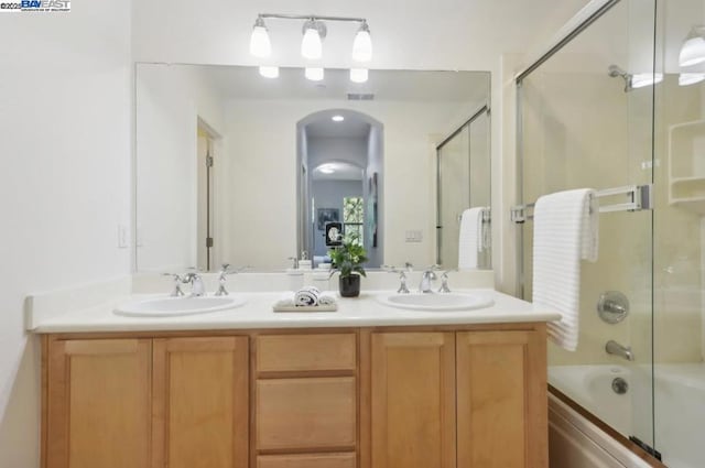 bathroom featuring shower / bath combination with glass door and vanity