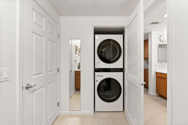 washroom with light tile patterned floors and stacked washer and dryer