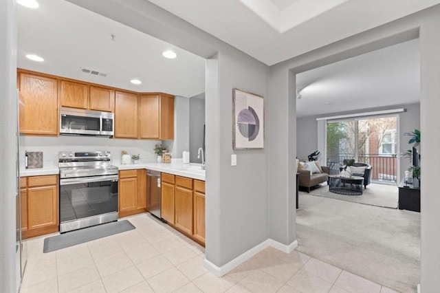 kitchen with sink, light colored carpet, and stainless steel appliances