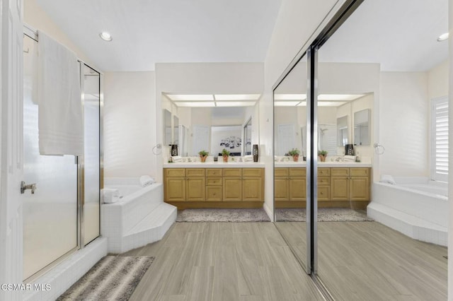 bathroom with plus walk in shower, hardwood / wood-style floors, and vanity