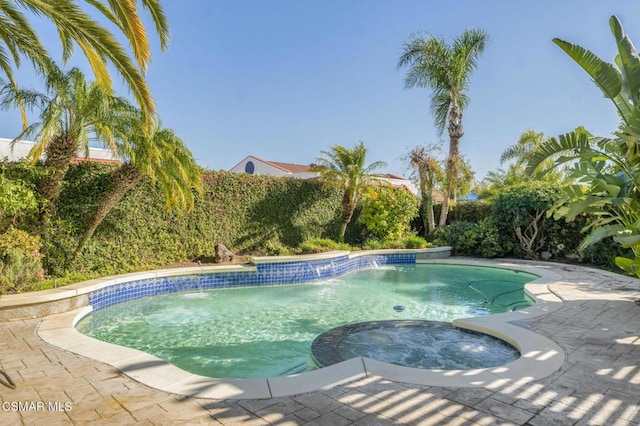 view of swimming pool with pool water feature and an in ground hot tub