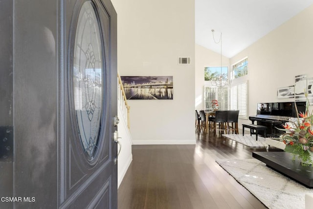 entryway with high vaulted ceiling, dark hardwood / wood-style flooring, and an inviting chandelier