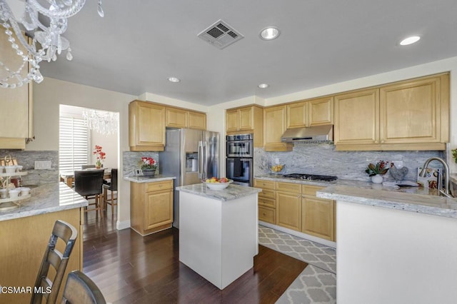 kitchen with light stone counters, stainless steel appliances, a notable chandelier, and a kitchen island