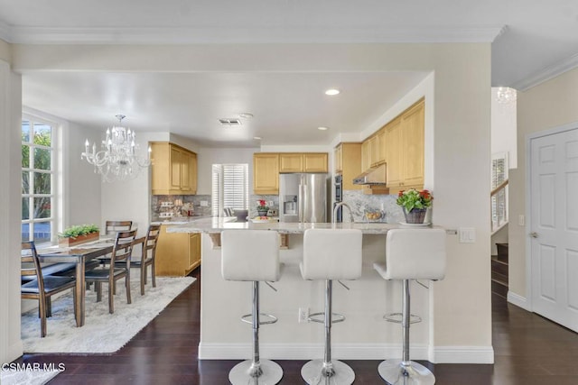 kitchen with stainless steel refrigerator with ice dispenser, plenty of natural light, backsplash, and light stone counters