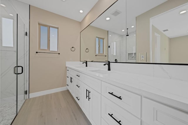 bathroom with a shower with shower door, hardwood / wood-style floors, and vanity