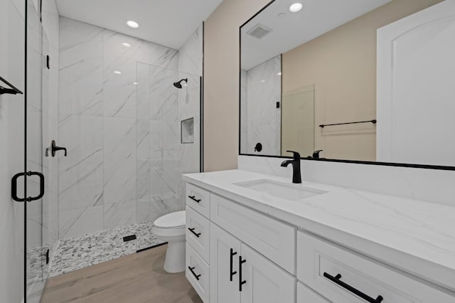 bathroom featuring toilet, vanity, walk in shower, and hardwood / wood-style flooring