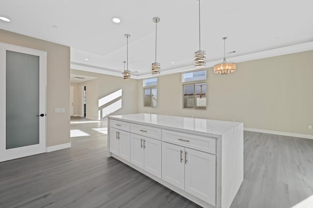 kitchen featuring white cabinetry, light hardwood / wood-style flooring, light stone counters, and decorative light fixtures