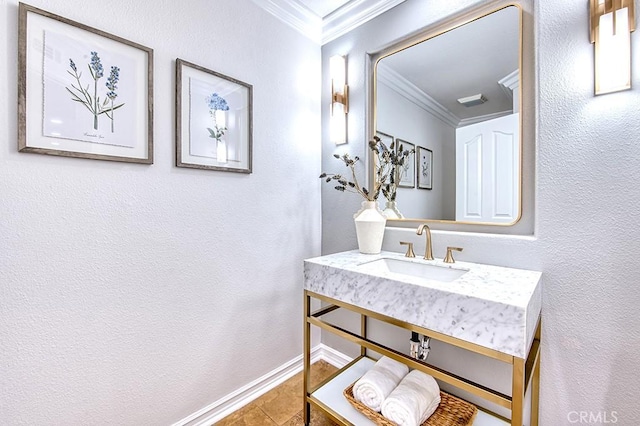 bathroom featuring a textured wall, tile patterned flooring, a sink, baseboards, and crown molding