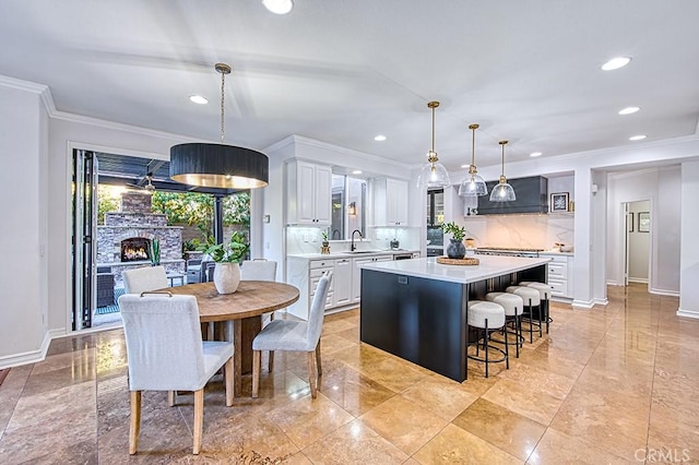 kitchen with a center island, hanging light fixtures, light countertops, white cabinetry, and a sink