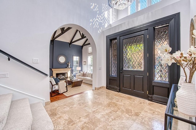 foyer entrance with high vaulted ceiling and a notable chandelier