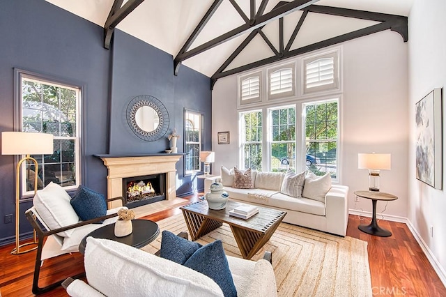 living room featuring a fireplace with flush hearth, wood finished floors, high vaulted ceiling, beamed ceiling, and baseboards