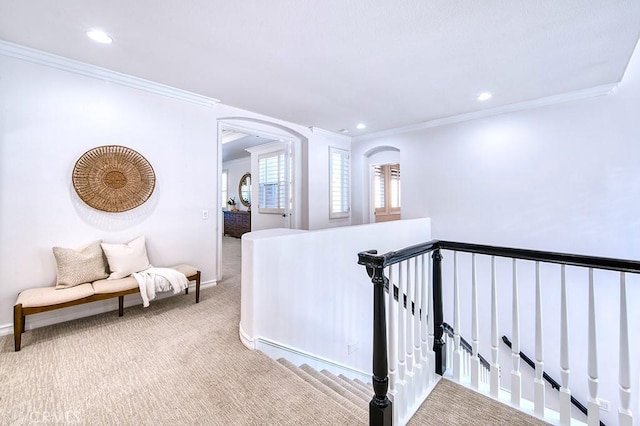 hall with arched walkways, light colored carpet, crown molding, and an upstairs landing