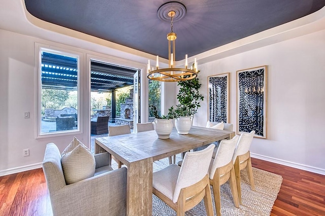 dining room with baseboards, a tray ceiling, dark wood finished floors, and a chandelier