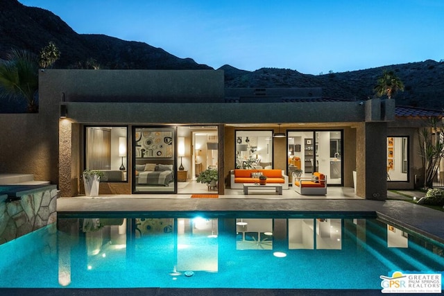 pool at dusk with a mountain view and outdoor lounge area