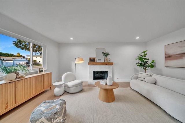 living room with light wood-type flooring and a tiled fireplace