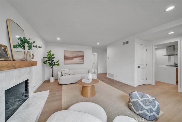 living room featuring a brick fireplace and light hardwood / wood-style flooring