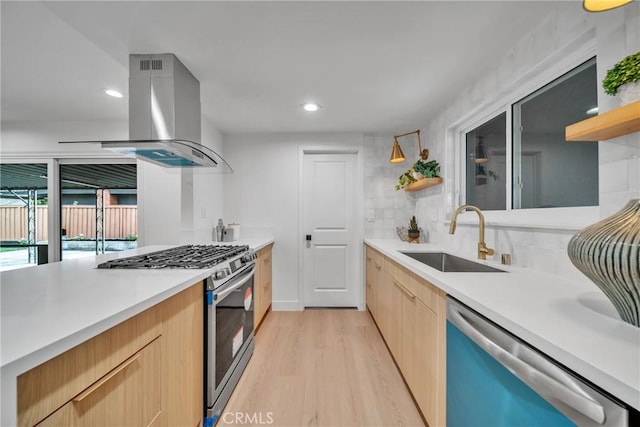 kitchen featuring island range hood, appliances with stainless steel finishes, light brown cabinetry, light hardwood / wood-style flooring, and sink