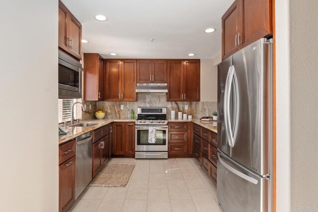 kitchen with light stone countertops, stainless steel appliances, decorative backsplash, sink, and light tile patterned flooring