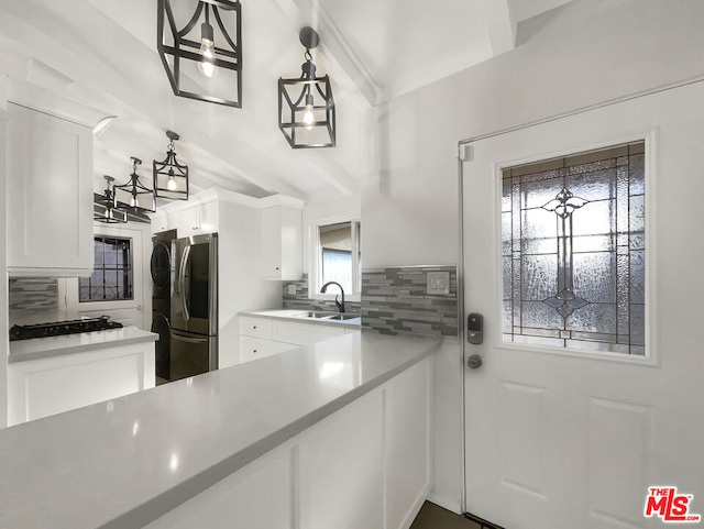 kitchen featuring white cabinetry, stainless steel fridge, tasteful backsplash, hanging light fixtures, and sink