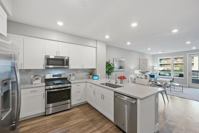 kitchen featuring white cabinets, kitchen peninsula, sink, and stainless steel appliances