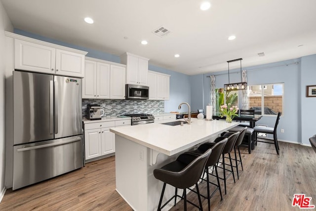 kitchen featuring an island with sink, appliances with stainless steel finishes, sink, and white cabinetry