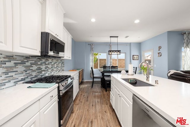 kitchen featuring hanging light fixtures, white cabinets, appliances with stainless steel finishes, and sink