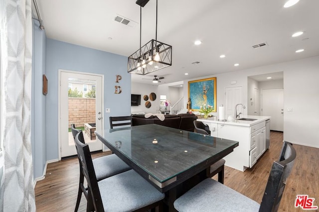 dining space with dark hardwood / wood-style floors, sink, and ceiling fan with notable chandelier