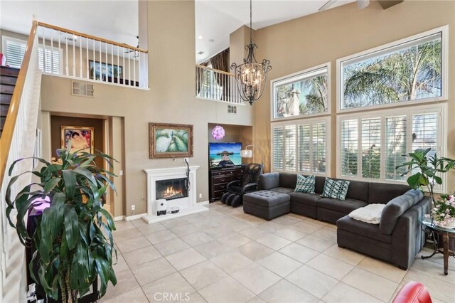 tiled living room with a high ceiling and a notable chandelier