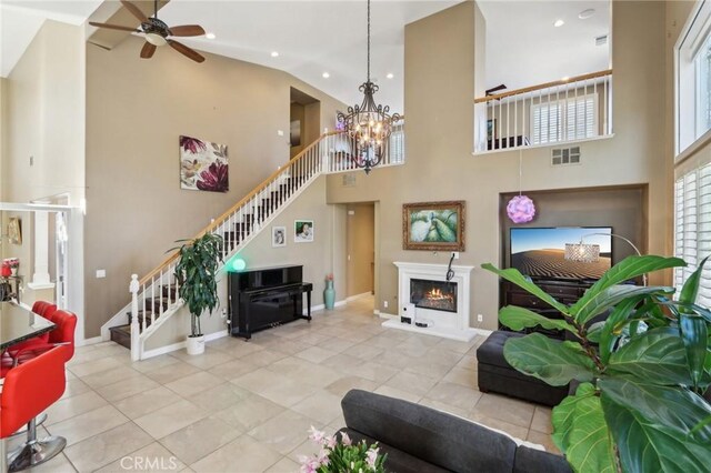 living room featuring light tile patterned floors, ceiling fan with notable chandelier, and high vaulted ceiling