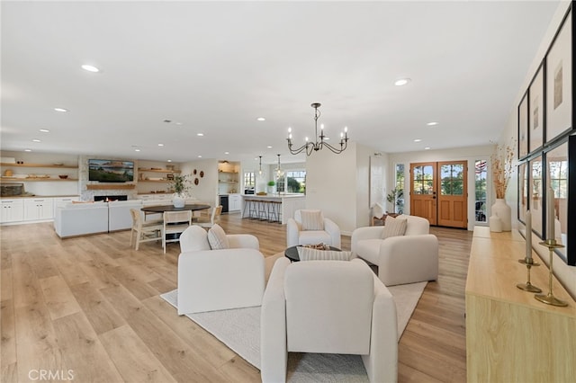 living room with a notable chandelier, a large fireplace, and light wood-type flooring