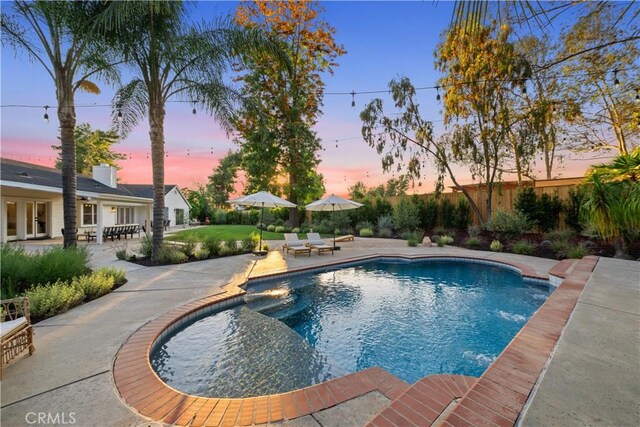 pool at dusk featuring a patio