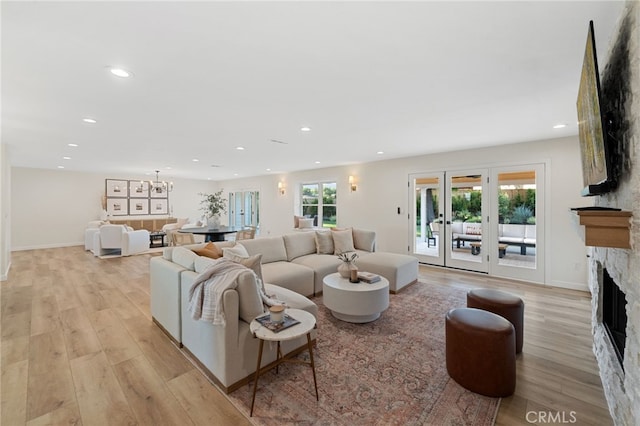 living room with a fireplace, light hardwood / wood-style floors, and french doors