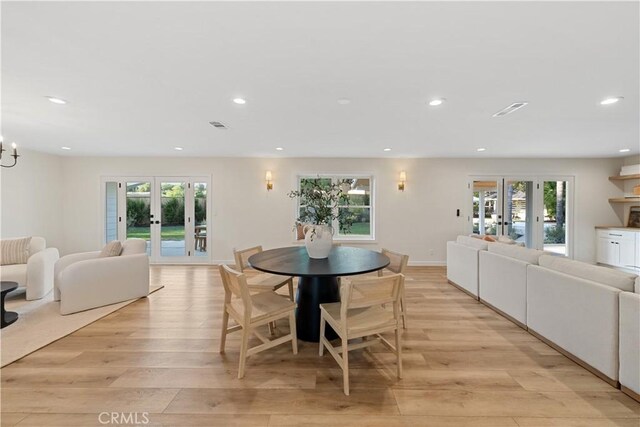 dining room with french doors, light wood-type flooring, and a healthy amount of sunlight