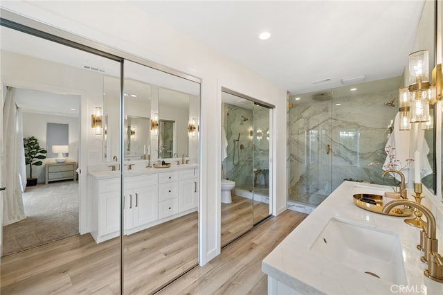 bathroom with wood-type flooring, vanity, toilet, and a shower with shower door