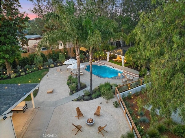 pool at dusk featuring an outdoor fire pit and a patio