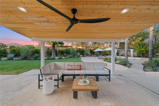 patio terrace at dusk featuring outdoor lounge area, a yard, and ceiling fan