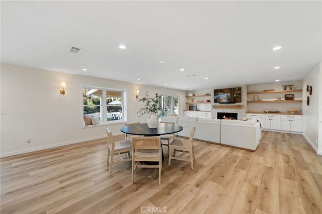 dining room with a fireplace and light wood-type flooring