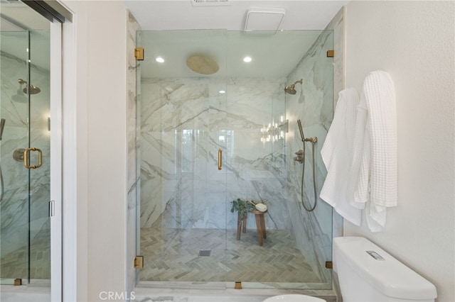 bathroom featuring toilet and a shower with shower door